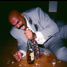 a man in a suit and tie is laying on the floor next to a bottle of liquor