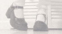 a black and white photo of a person 's feet wearing a pair of black shoes .