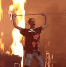 a man is standing in front of a fire on a stage holding a sword .