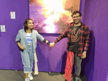 a man and a woman are holding hands in front of a painting