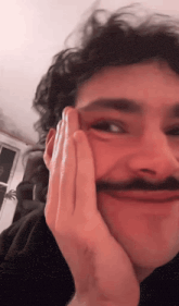 a man with a mustache is making a face with his hand on his face