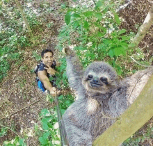 a man is taking a picture of a sloth with a selfie stick .