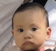 a close up of a baby making a sad face .