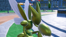 a statue of a green bug with white wings stands in a park