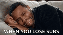 a man is crying while laying on a couch with a caption that says `` when you lose subs '' .