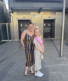 a woman and a little girl are standing in front of a sign that says pedestrians have priority over vehicles using lifts