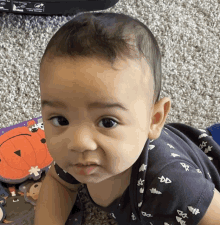 a baby wearing a shirt with bats on it is looking at the camera