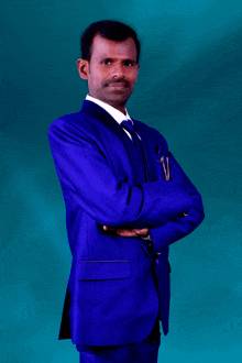 a man in a blue suit and tie with his arms crossed