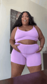 a woman in a purple top and shorts is standing in front of a wall