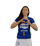 a woman wearing a blue itambé minas 8 jersey holds her arms up in the air