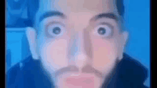 a man with a beard is making a funny face in front of a blue screen .