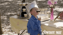 a boy wearing a graduation cap and a fake mustache is sitting at a table with the cowboy way written on the table cloth