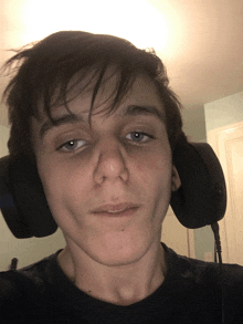 a young man wearing headphones is looking at the camera with his eyes closed