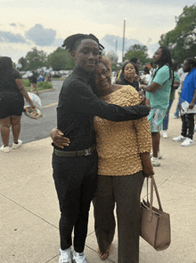 a boy in a black shirt is hugging an older woman in a tan top