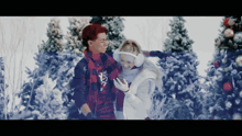 a man and woman are standing in the snow looking at their phone