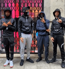 a group of young men wearing hoodies are standing in front of a store