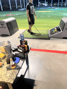 a man is standing on a golf course with a sign that says topgolf