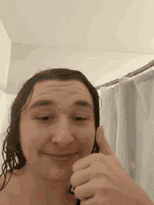 a man with wet hair giving a thumbs up