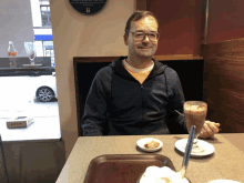 a man sits at a table with a glass of milkshake