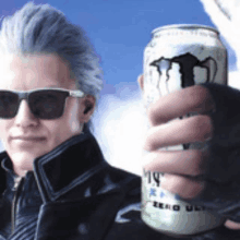 a man wearing sunglasses is holding up a can of monster energy drink