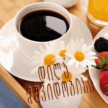 a cup of coffee on a saucer next to flowers and strawberries