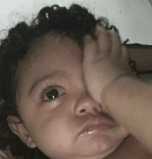 a baby is covering his face with his hand