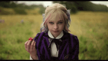 a girl in a purple and black suit is holding a red apple in her hand