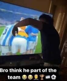 a man is standing in front of a television watching a soccer game and says bro think he part of the team
