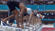 a group of female swimmers are getting ready to swim in front of a digital clock that reads 19 48 12