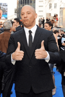 a man in a suit and tie is giving two thumbs up