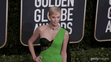 a woman in a green dress stands on a red carpet in front of a sign that says golden globe awards