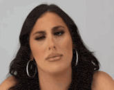 a woman wearing hoop earrings is making a face