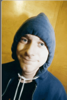 a man wearing a blue hoodie and a black shirt is smiling