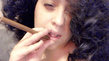 a woman with curly hair is smoking a cigar with her eyes closed