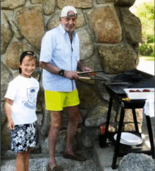 a man and a boy are standing in front of a stone wall cooking