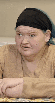 a woman wearing a headband and earrings looks at the camera