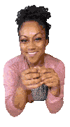 a woman in a pink shirt is smiling with her hands folded in front of her face