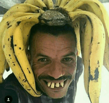 a man with a bunch of bananas on his head looks at the camera