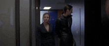 a man and a woman are walking in a hallway with a blue door that says exit