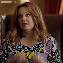 a woman in a floral shirt is sitting in a chair with the words nobodies written on the bottom