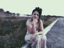 a woman in a lace dress sits on the side of the road with her hand on her chin