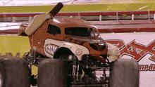 a monster truck that looks like a hot dog is driving in front of a sign that says pax motorsports