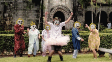 a group of people wearing masks and tutus are dancing in front of a brick building with the words misshafuzzyface tumblr visible