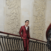 a man in a red suit stands on a railing