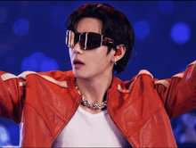 a man wearing a red leather jacket and sunglasses is standing on a stage .