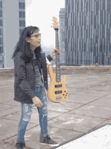 a man holding a guitar on a rooftop with a building in the background and a shirt that says tcl