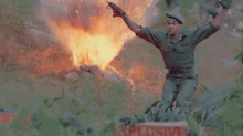 a man in a military uniform is standing in front of a fire with a sign that says explosive in the foreground