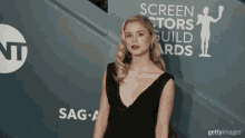 a woman in a black dress stands in front of a sign that says screen actors guild