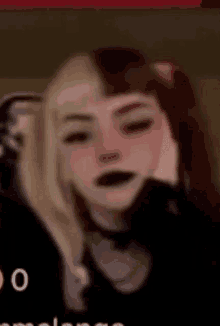 a girl with half blonde and half brown hair is wearing black lipstick .