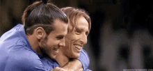 two soccer players are hugging each other and smiling .